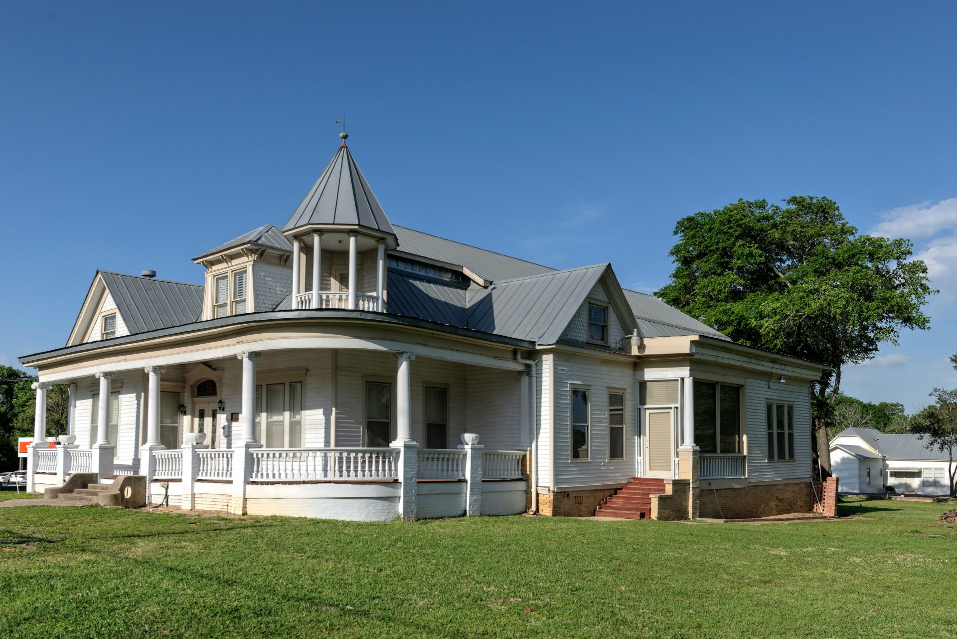 white and blue wooden house near green grass field under blue sky during daytime